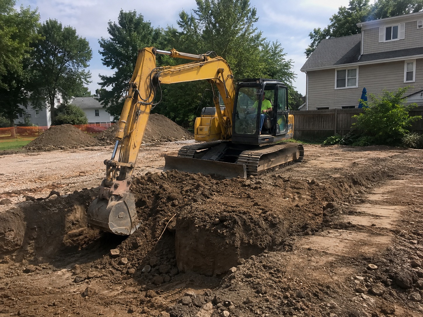 Excavator digging foundation trenches on a Hamilton building site